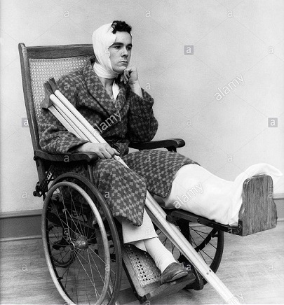 1930s-man-in-wheelchair-leg-cast-bandage-head-neck-crutches-aakm3g